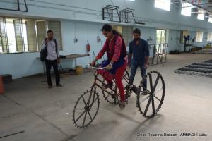 Local student testing the TricTrac tricycle tractor inside a manufacturing hall in Amrita University, Coimbatore